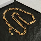 Gold chain necklace set with small hanging charm and rectangular logo tags