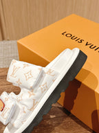 White Louis Vuitton monogram slide sandals with tan buckle and dark rubber sole