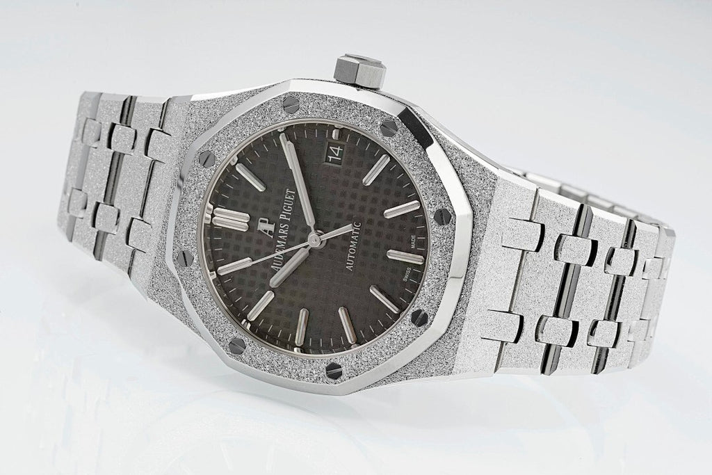 Audemars Piguet Royal Oak watch with dark dial, silver bracelet, and beveled octagonal bezel.