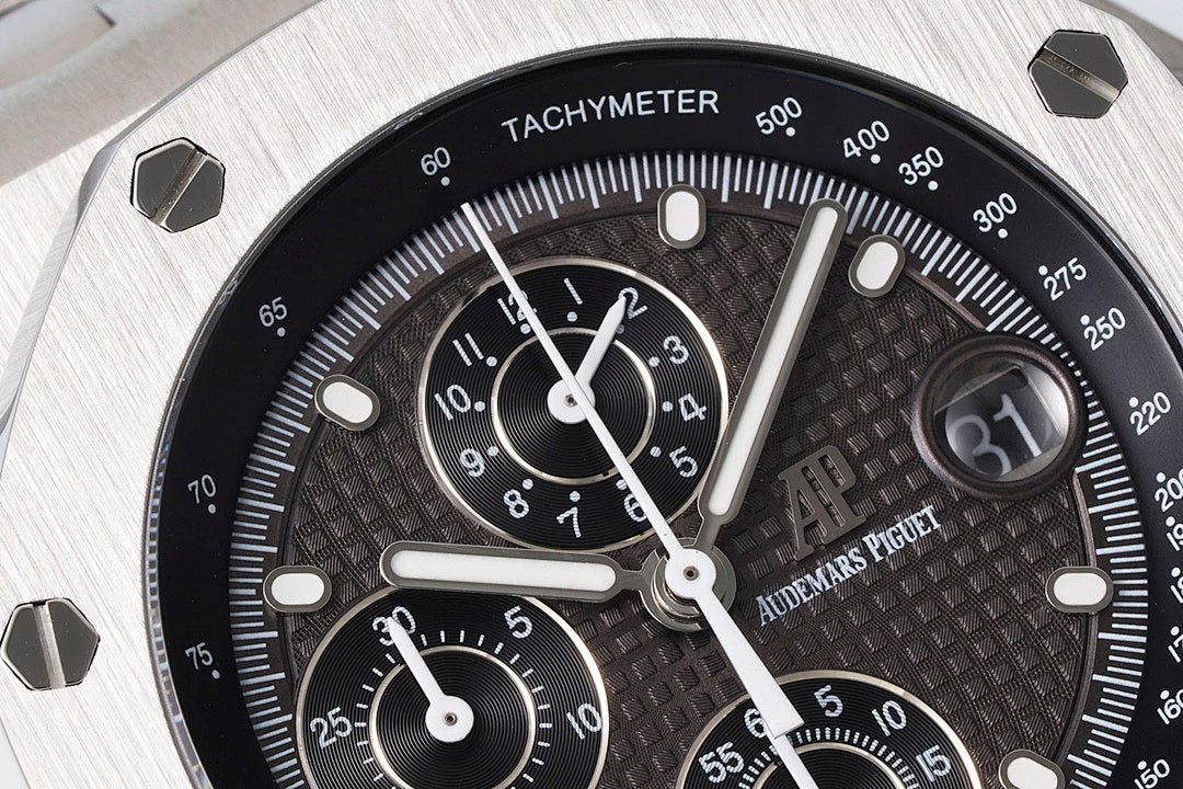 Audemars Piguet chronograph dial close-up with black face, subdials, and tachymeter scale.