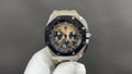 Luxury sports watch with black dial, gold-toned subdials, silver bracelet