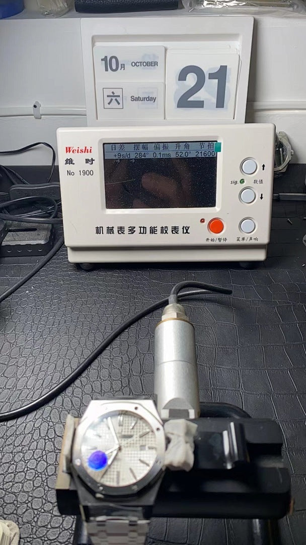Stainless steel wristwatch on testing rig, white dial with blue markings