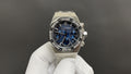 Stainless steel wristwatch with blue chronograph dial and diamond-style bezel, on glove