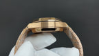 Gold-tone wristwatch case with crown and bracelet links, side view