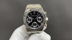 Audemars Piguet Royal Oak watch with black dial, silver bezel, three subdials, metal bracelet.