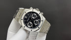 Audemars Piguet watch angled view with black dial, bezel screws, metal bracelet band.