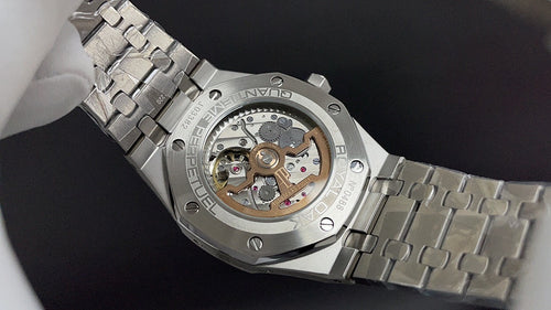 Stainless steel wristwatch showing open caseback movement and metal bracelet