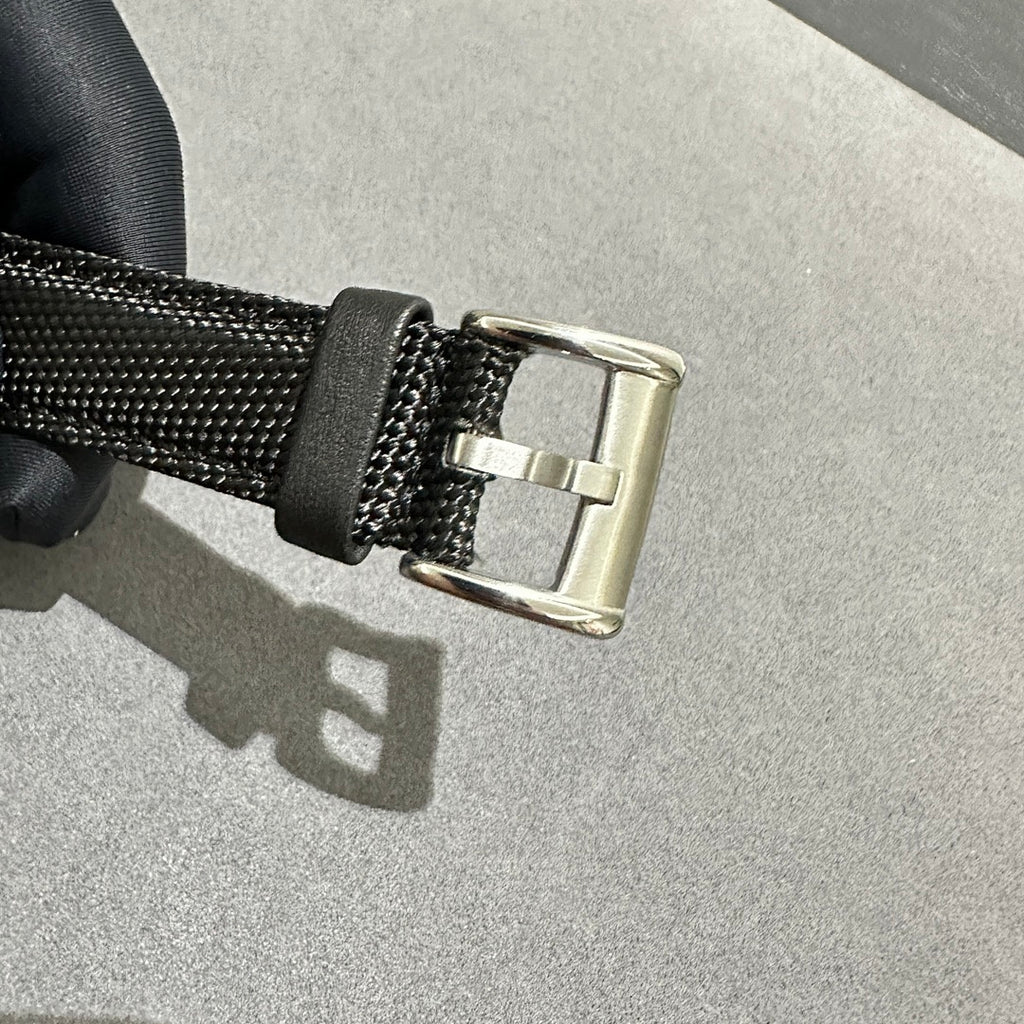 Black textured watch strap with metal buckle clasp, black fabric and silver hardware