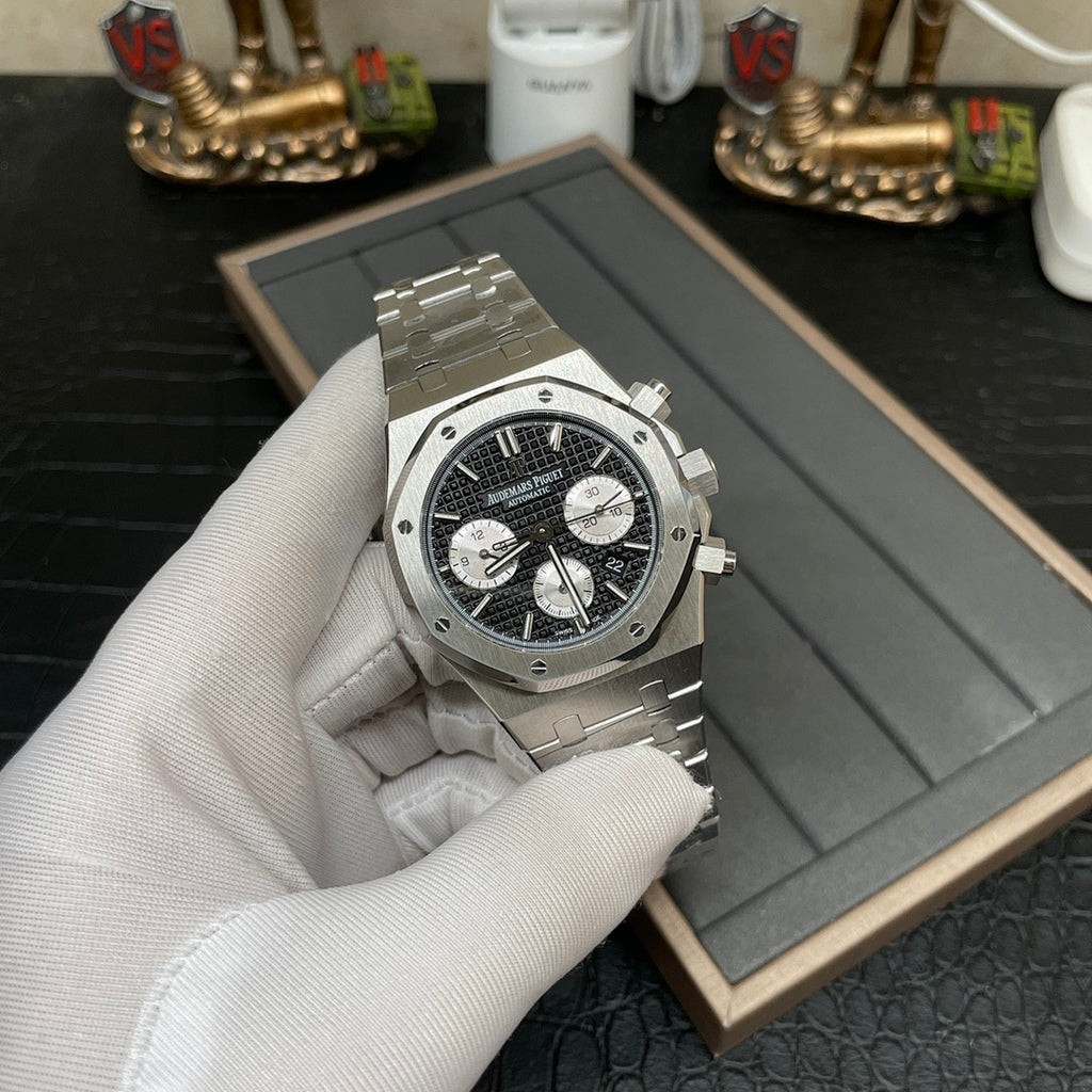 Audemars Piguet chronograph watch with black dial and steel bracelet, held in gloved hand
