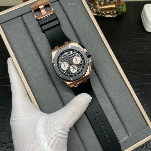 Rose gold chronograph watch with black dial and black rubber strap in a display box