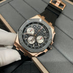 Rose gold chronograph watch with black dial and three subdials on black rubber strap