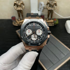 Rose gold chronograph watch with black dial and three subdials, on black rubber strap