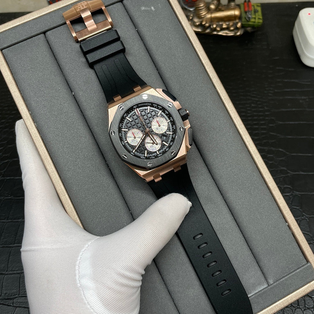 Rose gold chronograph watch with black dial and black rubber strap lying in a box