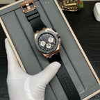 Rose gold chronograph watch with black dial and black rubber strap lying in a box