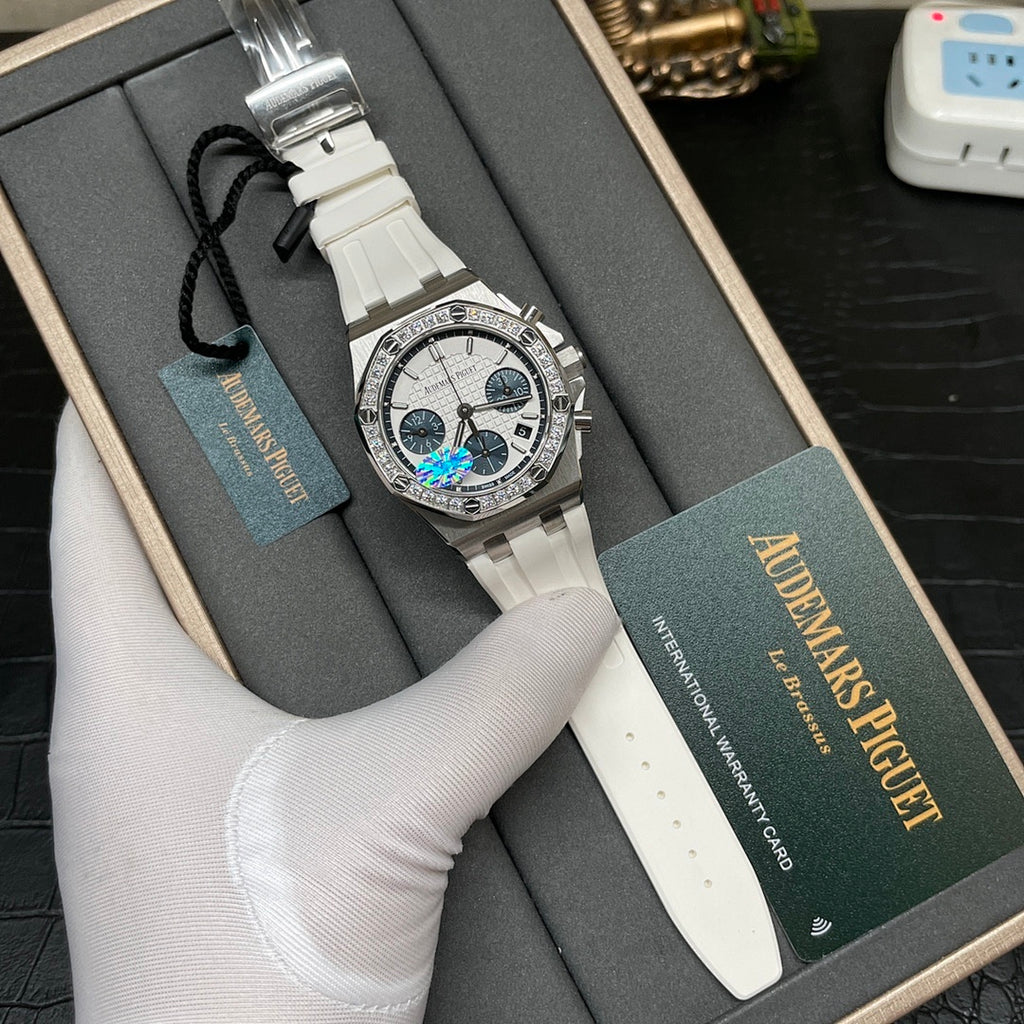 Diamond bezel luxury wristwatch with silver case, white strap, and presentation box