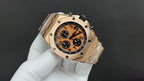 Audemars Piguet chronograph watch, gold-tone case, orange dial, angled view