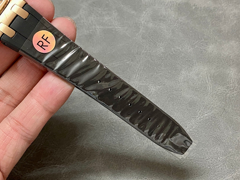 Black rubber watch strap with rose gold-tone clasp end and engraved marks