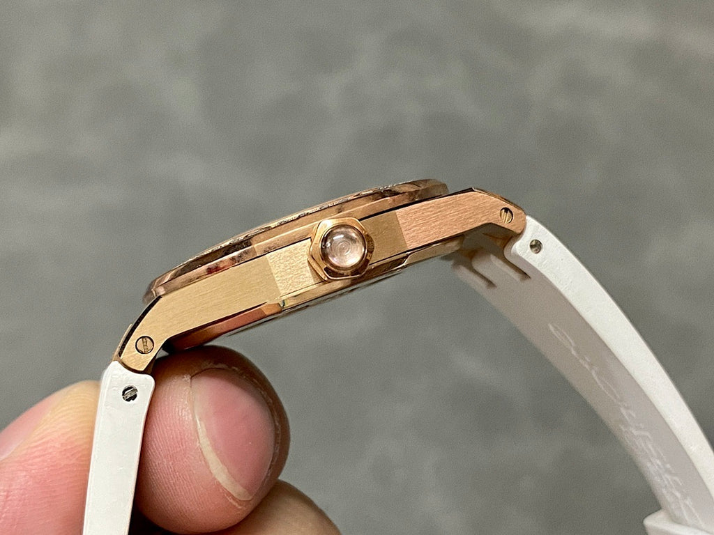 Rose gold-tone watch case with crown and white rubber strap, side view.