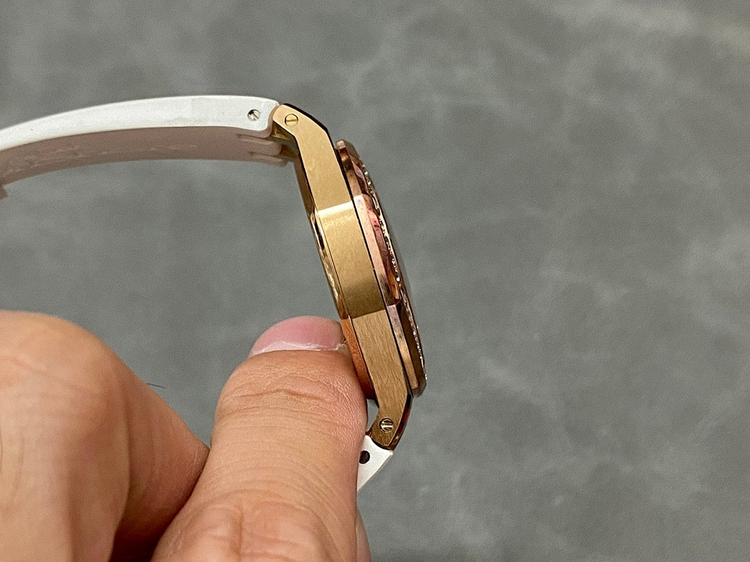 Rose gold-tone watch case side with screws and white rubber strap, angled view.