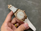 Rose gold-tone watch with white dial, diamond bezel, and white rubber strap.