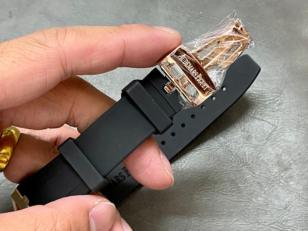 Black rubber watch strap with rose-gold clasp and visible screw details.