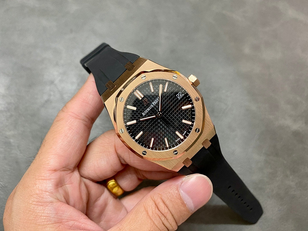 Rose-gold luxury wristwatch with black textured dial and black rubber strap on hand.