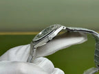 Silver-tone steel watch with side profile and black dial, held on wrist