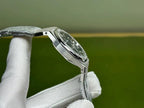 Silver-tone steel watch with curved case and bracelet links, held by white gloves