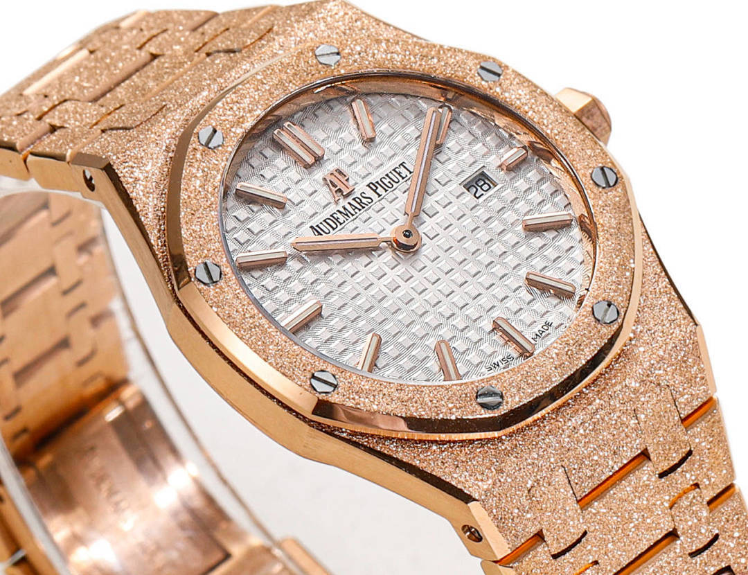 Audemars Piguet rose gold watch face with white textured dial and baton hour markers.