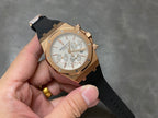 Rose gold chronograph watch with silver dial and black rubber strap, full front view