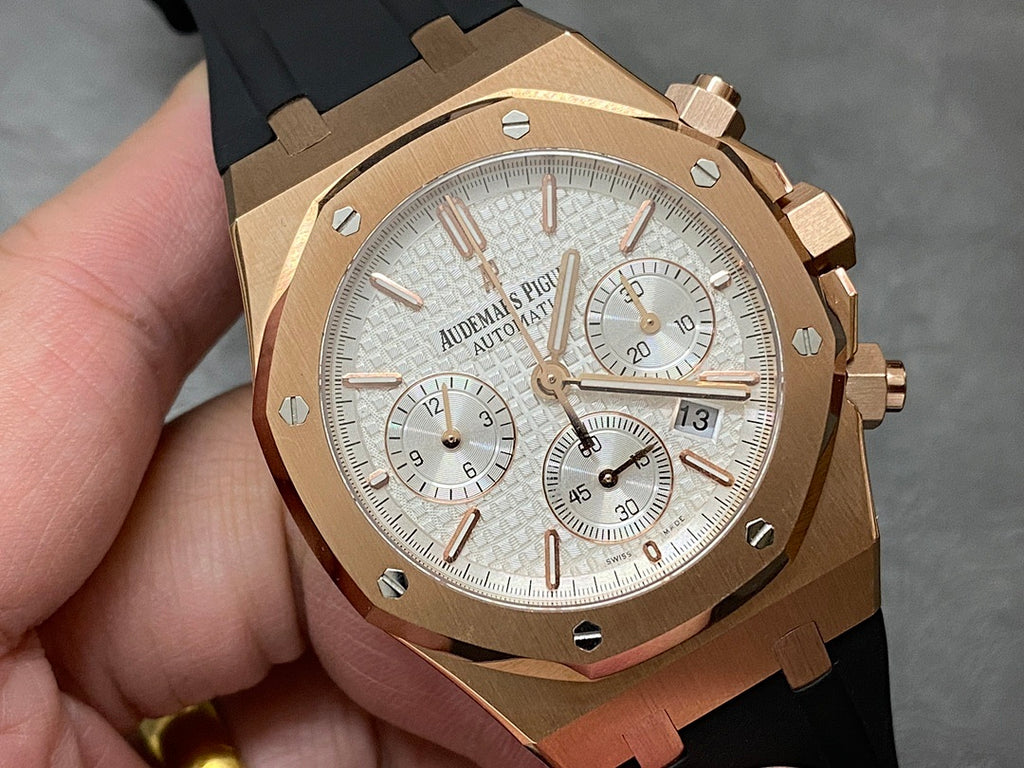 Rose gold chronograph watch with silver dial, black rubber strap, subdials and date window