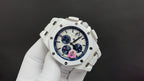 Audemars Piguet watch angled view, white case, blue dial, colored central emblem.
