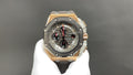 Octagonal luxury watch with dark dial, gold-tone bezel, and gray rubber strap