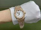 Gold-tone Audemars Piguet wristwatch with white dial and textured bracelet on a wrist