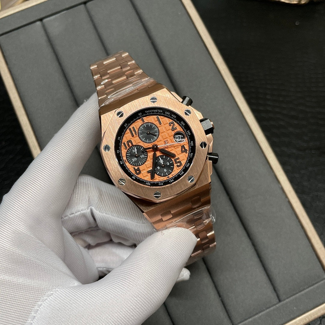 Rose-gold chronograph wristwatch with orange dial, black pushers, and metal link bracelet