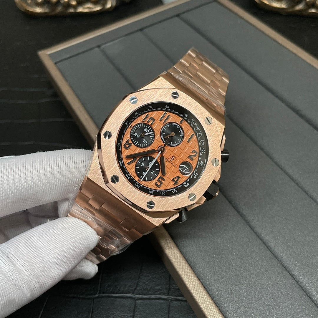 Rose-gold chronograph wristwatch with orange dial, black subdials, and metal bracelet