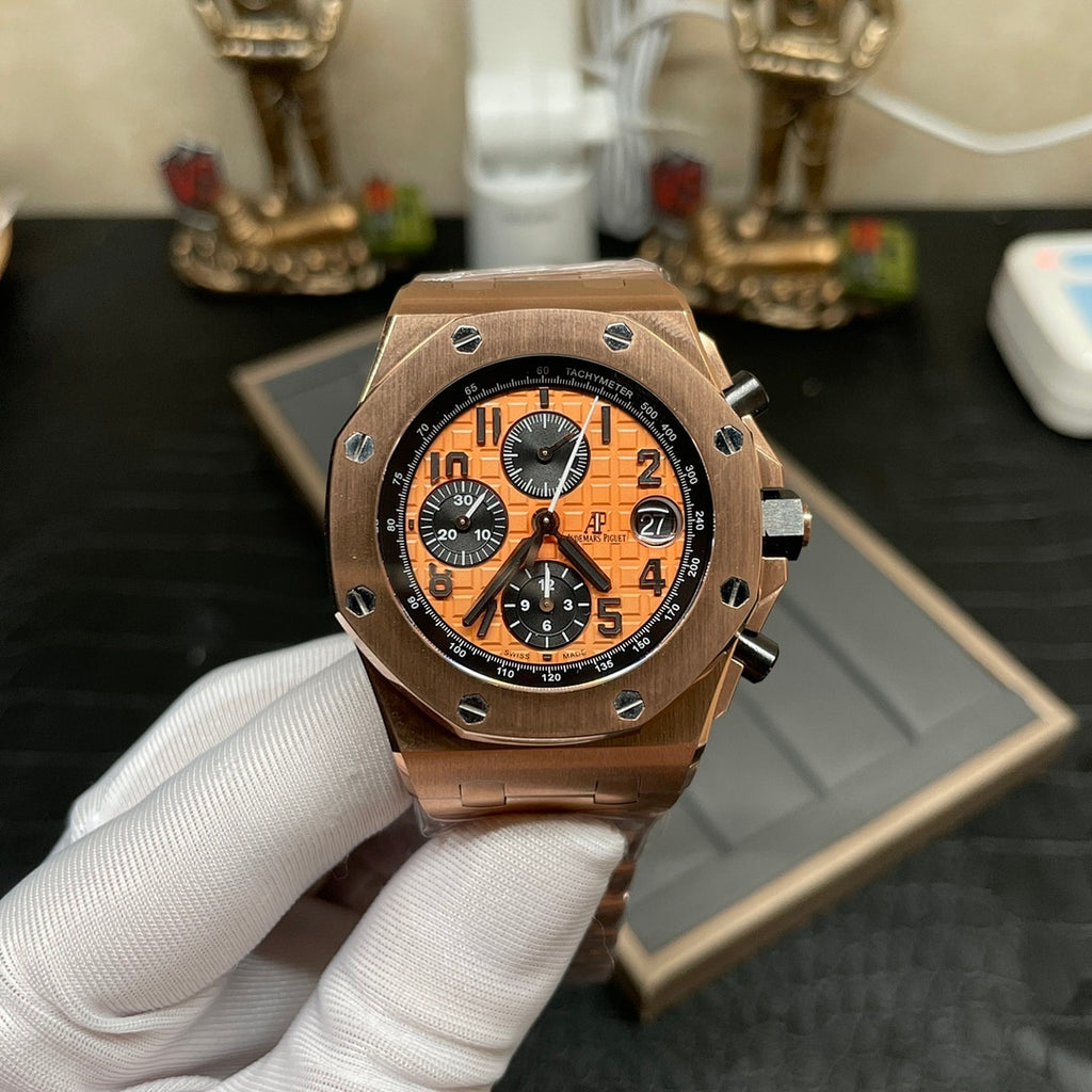 Rose-gold chronograph wristwatch with orange dial and black subdials on metal link bracelet