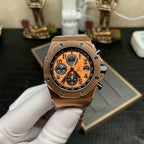 Rose-gold chronograph wristwatch with orange dial and black subdials on metal link bracelet