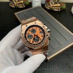 Rose-gold chronograph wristwatch with orange dial, black subdials, and side view of bracelet