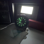 Chronograph watch with dark dial lit green, steel case, gray strap