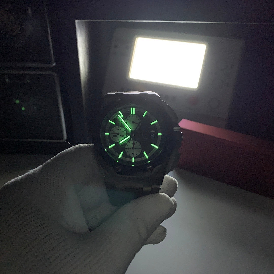 Chronograph watch with dark dial lit green, steel case, gray strap