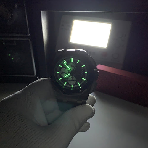 Chronograph watch with dark dial lit green, steel case, gray strap