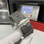 Watch crown-side view with gray rubber strap and brushed steel case