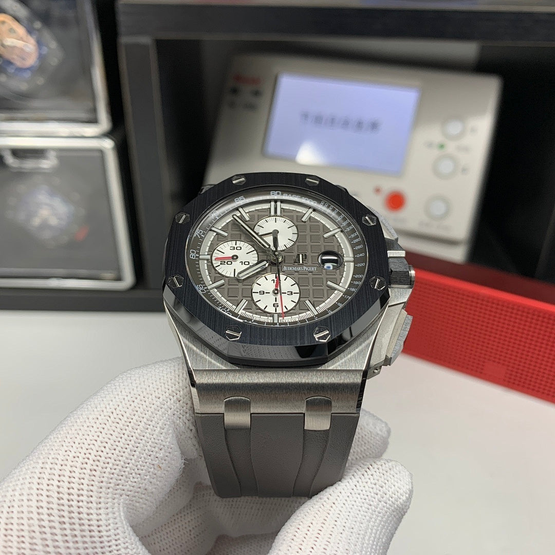 Chronograph watch front view with dark dial, steel case, and gray rubber strap