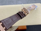 Brown leather strap with stitched edges and rose gold clasp, watch resting on holder