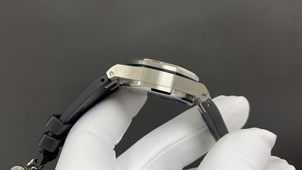 Stainless steel watch case with black rubber strap, side view.
