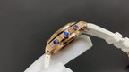 Audemars Piguet watch angled side view, gold case with blue accents, on white strap