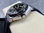 Luxury sports watch with dark dial, yellow indices, and dark rubber strap from side
