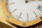 Close-up of gold-tone wristwatch white dial with raised indices and Swiss Made text