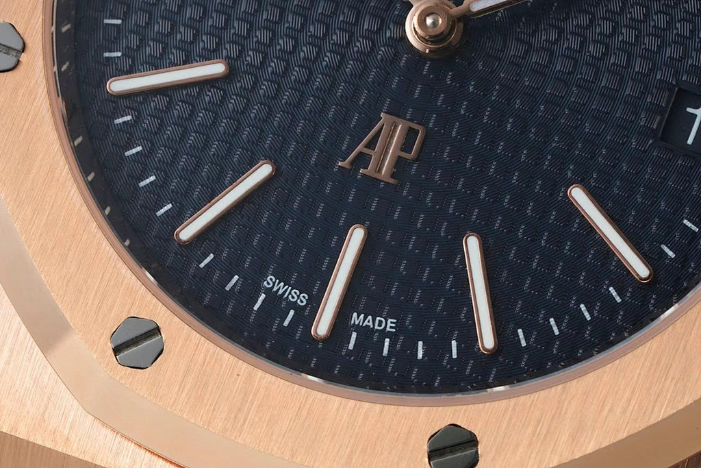 Dark blue wristwatch dial close-up with baton hour markers and logo at center.